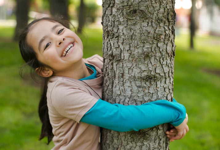girl-holding-tree-smiling